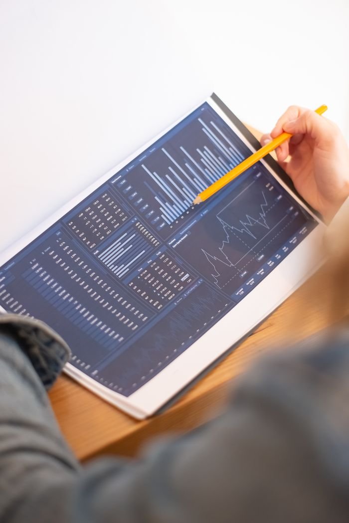 Capabilities A close-up of a person analyzing blue graph data with a yellow pencil.